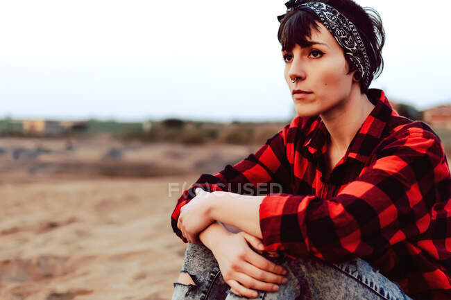 Mulher hipster pensativo sentado na praia de areia — Fotografia de Stock