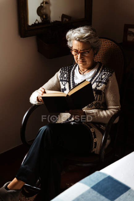 Літня жінка читає за вікном з ентузіазмом — стокове фото