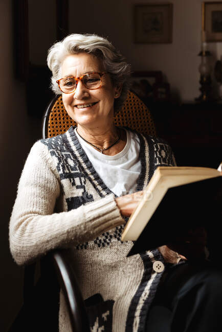 Donna anziana che legge alla finestra con entusiasmo — Foto stock