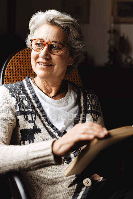 Mulher idosa lendo por janela com entusiasmo — Fotografia de Stock