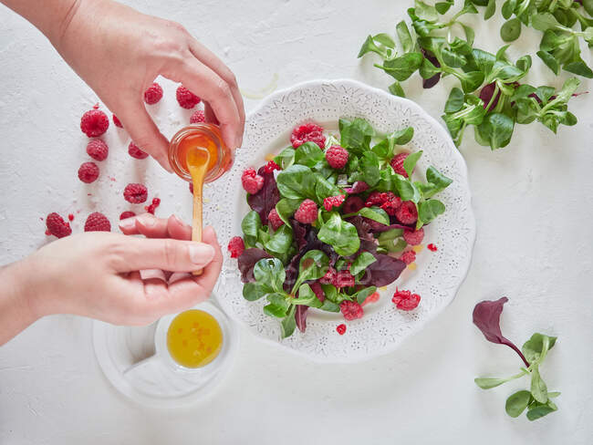 Person gibt Himbeersaft in Obstsalat — Stockfoto