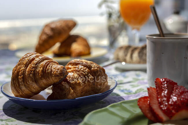 Homemade full brunch breakfast in sunlight with croissants, strawberries, tea or coffee and orange juice — Stock Photo