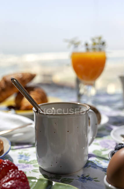 Desayuno completo en el almuerzo casero a la luz del sol con té o café en una taza, huevos cocidos y jugo de naranja - foto de stock