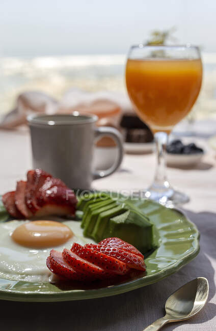 Homemade full healthy breakfast in sunlight with eggs, avocado, strawberries, blueberries, sponge cake, croissants, toast, tea, coffee and orange juice — Stock Photo