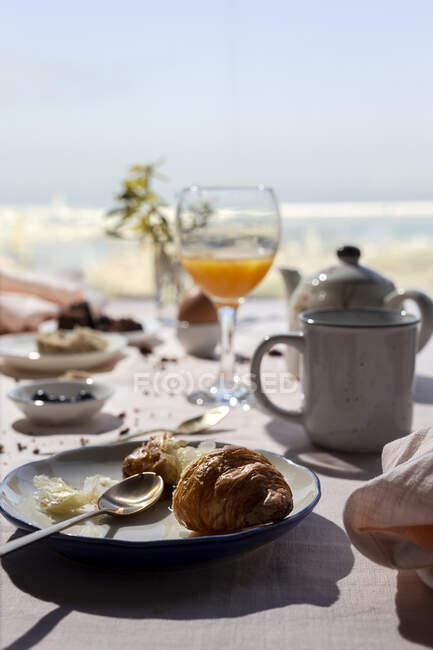 Pequeno-almoço caseiro completo sob luz solar com croissants, chá, café e suco de laranja — Fotografia de Stock