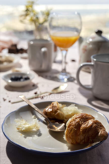 Pequeno-almoço caseiro completo sob luz solar com croissants, chá, café e suco de laranja — Fotografia de Stock
