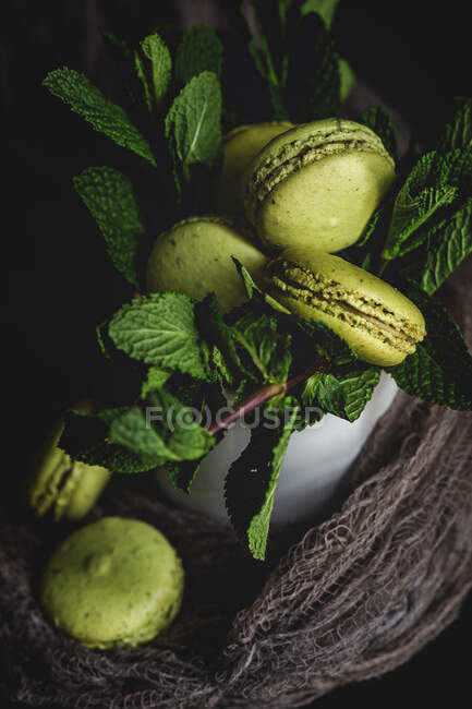 Homemade green macarons green with mint on dark background. Dark food. — Stock Photo