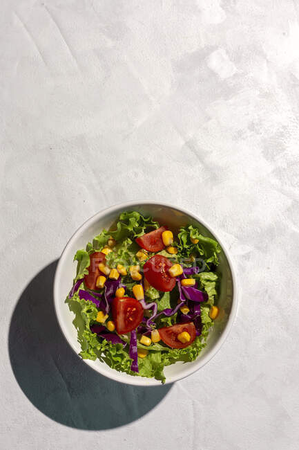 Salada de alface fresca com tomate cereja, cebola vermelha e milho, luz solar em fundo rosa de cima. Comida saudável. Comida Vegan . — Fotografia de Stock