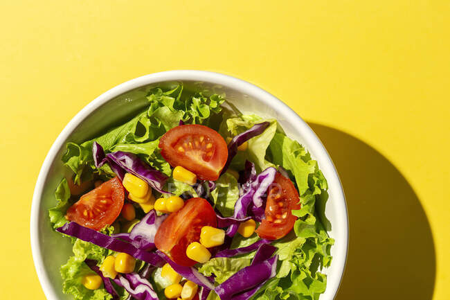 Salada de alface fresca com tomate cereja, cebola vermelha e milho, luz solar em fundo rosa de cima. Comida saudável. Comida Vegan . — Fotografia de Stock