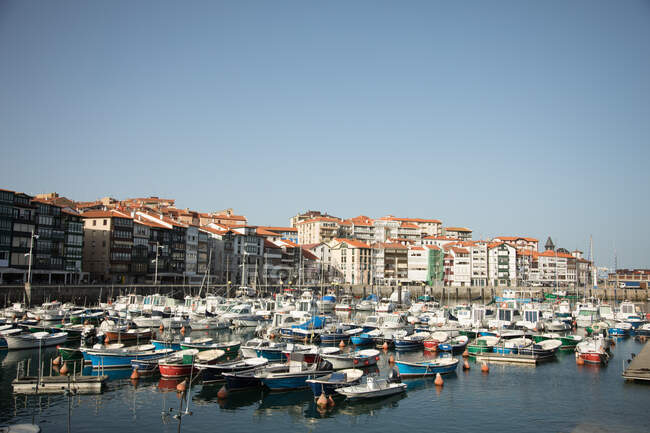 На човнах і яхтах у гавані курортного міста на набережній вздовж району з багатоповерховими будівлями під блакитним небом в Іспанії. — стокове фото