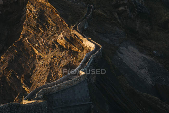 Von oben herrliche Landschaft mit Pfad, der entlang einer Steinbrücke mit Treppe auf den Gipfel des Berges führt, am sonnigen Abend entlang des Felsgrats — Stockfoto