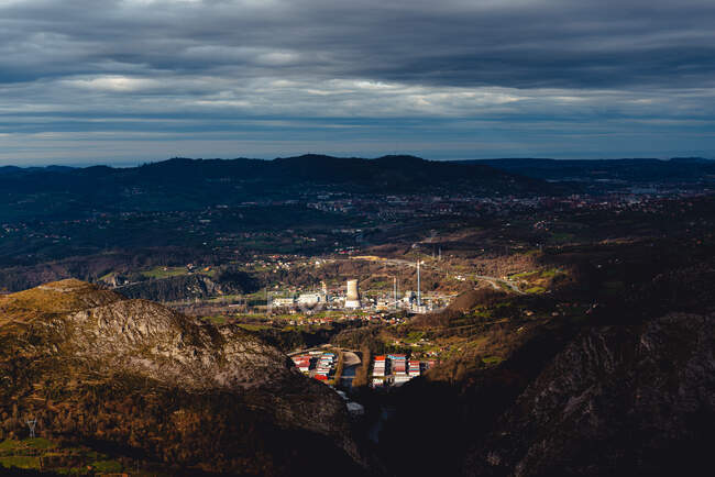 Von oben Fabrik im Tal gegen Stadt am Fuße der Berge am Horizont unter grauem bewölkten Himmel in Monsacro — Stockfoto