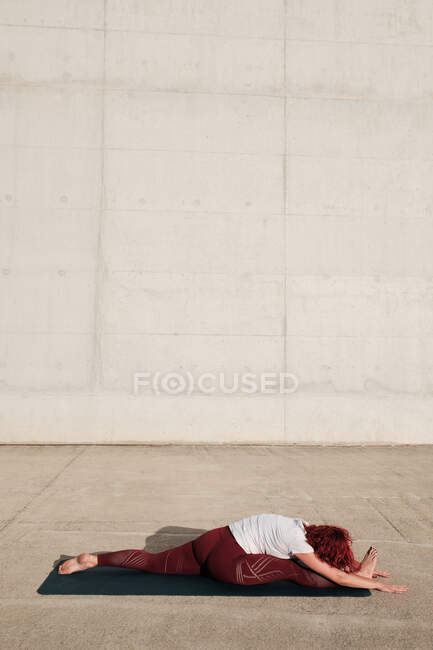 Вид збоку анонімної босоніж жінки в спортивному одязі робить йогу в позі мавпи вперед вигин позу на килимку — стокове фото