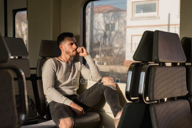 Pensativo joven pasajero masculino sentado en el vagón del metro - foto de stock