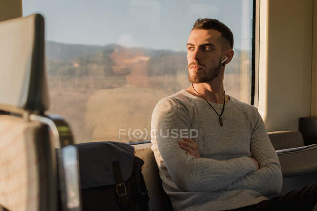 Jeune homme réfléchi écoutant de la musique dans une voiture de métro — Photo de stock