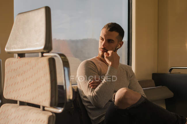 Jeune homme réfléchi écoutant de la musique dans une voiture de métro — Photo de stock