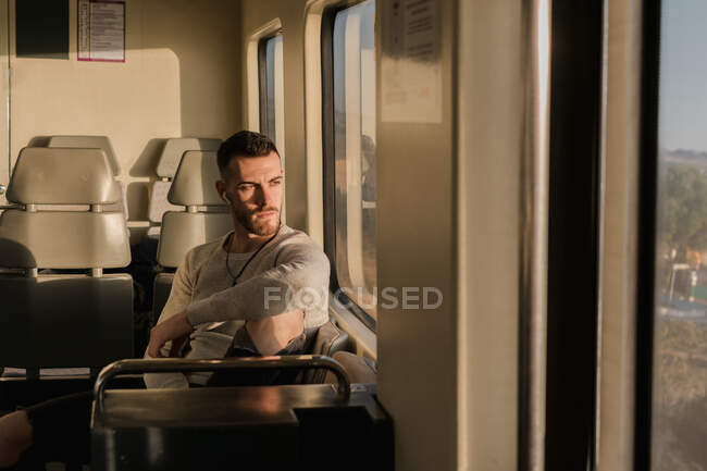 Pensativo jovem passageiro do sexo masculino ouvindo música no metrô — Fotografia de Stock