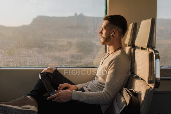 Concentrated male passenger using laptop in train — Stock Photo
