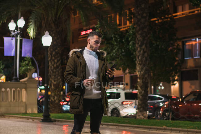 Serious young man using smartphone in street — Stock Photo