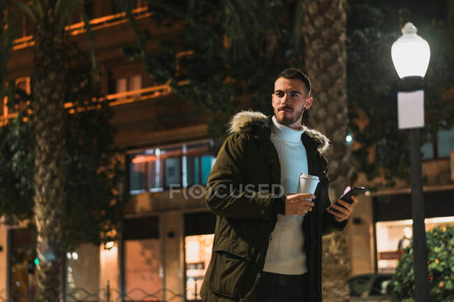 Smiling young man using smartphone in street — Stock Photo