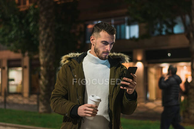 Schwerer junger Mann benutzt Smartphone auf der Straße — Stockfoto