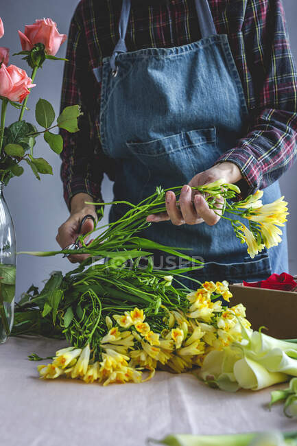 Fleuriste professionnelle féminine méconnaissable faisant des bouquets de différents types. Des roses. Fleurs jaunes. Baies — Photo de stock