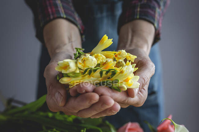 Florista profesional femenina irreconocible haciendo ramos de varios tipos. Rosas. Flores amarillas. Calas - foto de stock