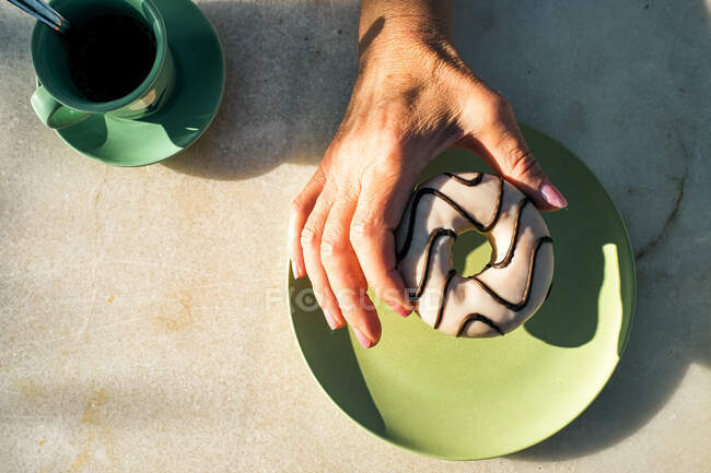 Жінка тримає апетитний пончик з глазур і передбачаючи чудовий смак. — стокове фото