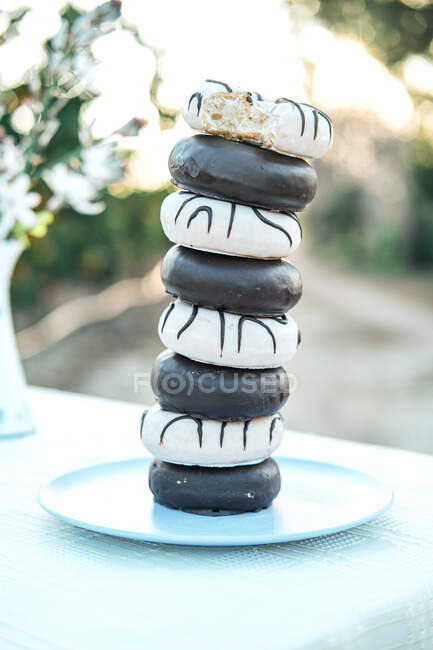 Yummy donuts with icing and chocolate ganache stacked on plate — Stock Photo