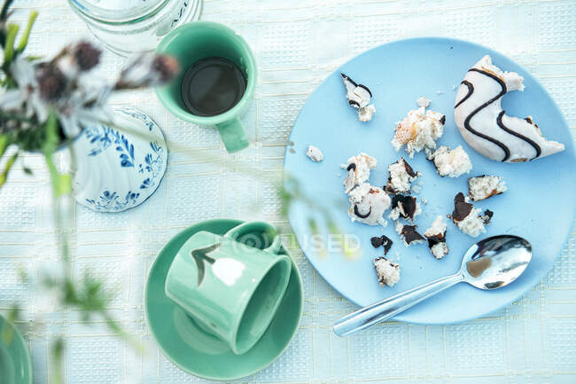 Empty cup on saucer and plate of pastry crumbs with spoon on table — Stock Photo