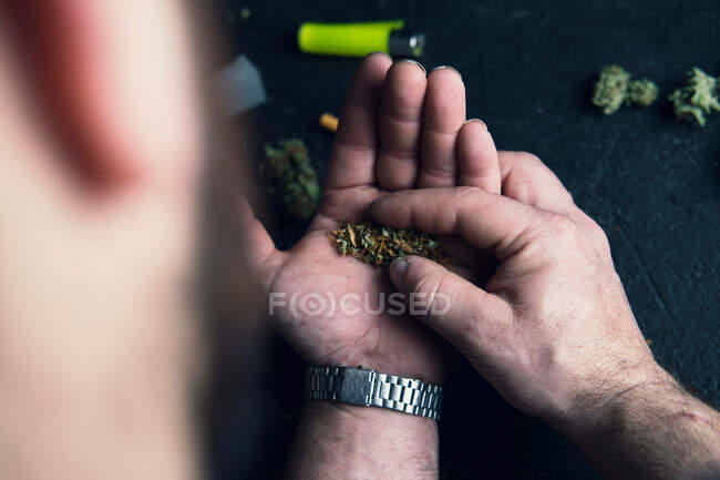 Unrecognizable male making cannabis joint at home — Stock Photo