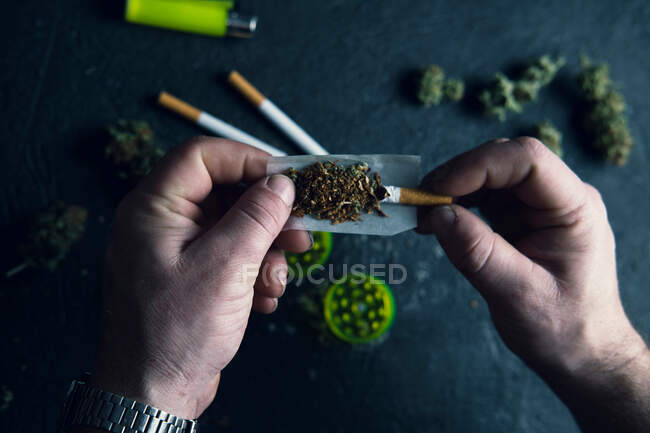 Homme méconnaissable faisant joint de cannabis à la maison — Photo de stock
