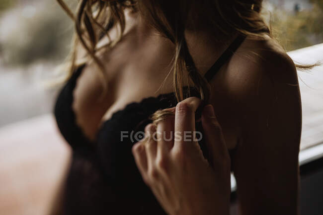 Crop from above of provocative female wearing black lingerie and touching hair while standing on terrace — Stock Photo