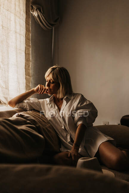 Verführerische Blondine sitzt auf Sofa im Wohnzimmer — Stockfoto