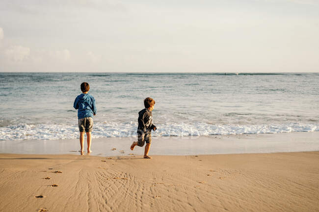 Безтурботні хлопчики насолоджуються морськими хвилями та піщаним пляжем під час поїздки на вихідні до моря — стокове фото