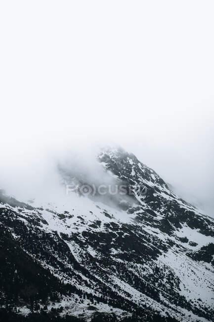 Paisagem fria severa do inverno com picos nevados da montanha com nevoeiro e tempestade de neve quebrando por toda parte — Fotografia de Stock