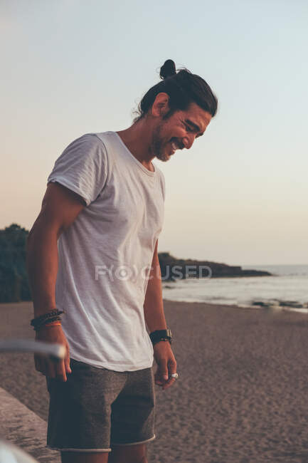 Positive man with motorbike standing at seaside — Stock Photo