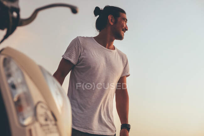 Uomo positivo con moto in piedi al mare — Foto stock