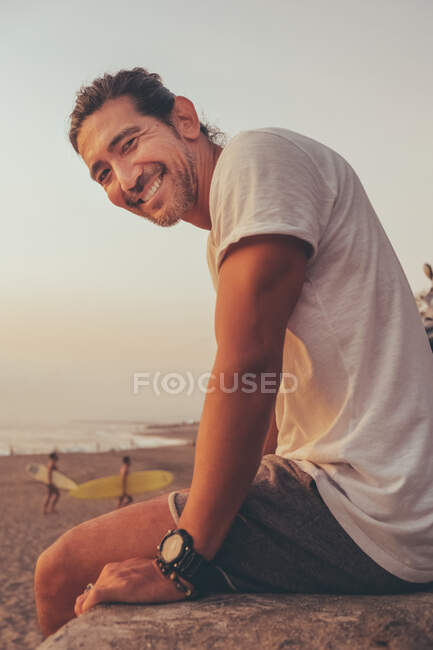 Homme heureux avec moto profitant du coucher de soleil sur la plage — Photo de stock