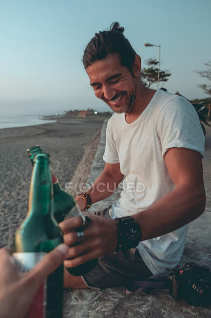 Amis griller avec de la bière sur la plage du coucher du soleil — Photo de stock