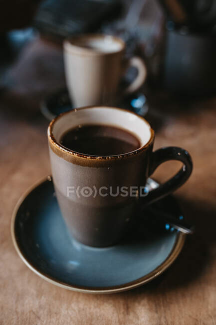 Café quente em uma caneca rústica na mesa de madeira — Fotografia de Stock