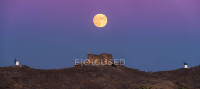 Снизу живописный пейзаж заброшенной крепости на вершине горы, освещенной полнолунием ночью в Толедо — стоковое фото