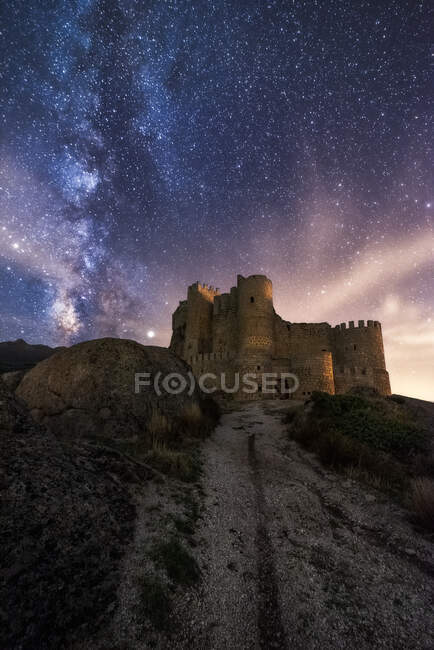 Amazing scenery of abandoned ancient palace on mountain under colorful starry sky at night — Stock Photo