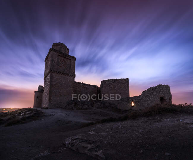Dal basso pittoresco scenario di resti abbandonati di antico castello sotto il cielo viola tramonto — Foto stock