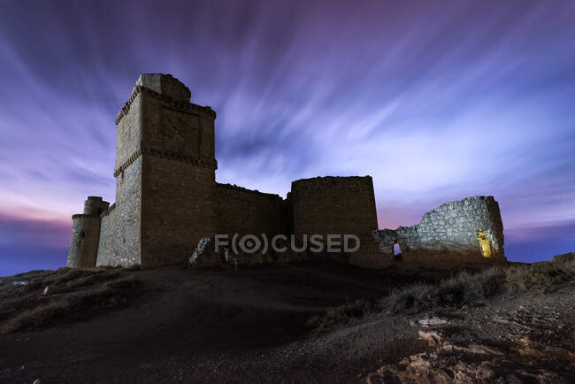 Dal basso pittoresco scenario di resti abbandonati di antico castello sotto il cielo viola tramonto — Foto stock