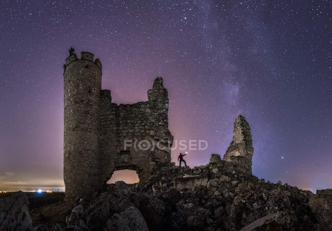 Снизу вид анонимного туриста с фонариком исследующий разрушенный старый замок под Млечный Путь в звездную ночь — стоковое фото