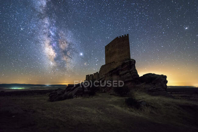 Dal basso turista irriconoscibile esplorare castello medievale in rovina sotto il cielo stellato con Via Lattea di notte — Foto stock