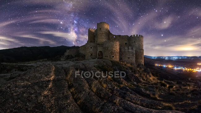 Increíble paisaje de palacio antiguo abandonado en la montaña bajo el colorido cielo estrellado en la noche - foto de stock