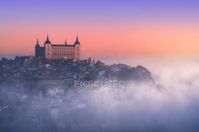 Desde arriba maravilloso paisaje de castillo medieval construido sobre la ciudad en nebuloso amanecer colorido - foto de stock