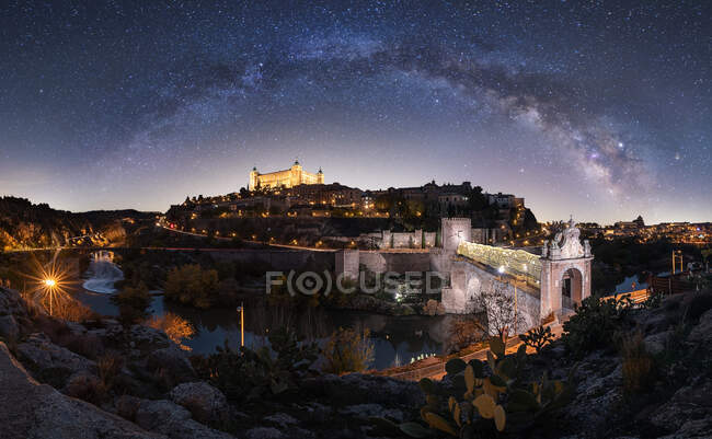 Vista dell'occhio di pesce della città medievale illuminata di Toledo sotto la Via Lattea sul cielo stellato di notte — Foto stock